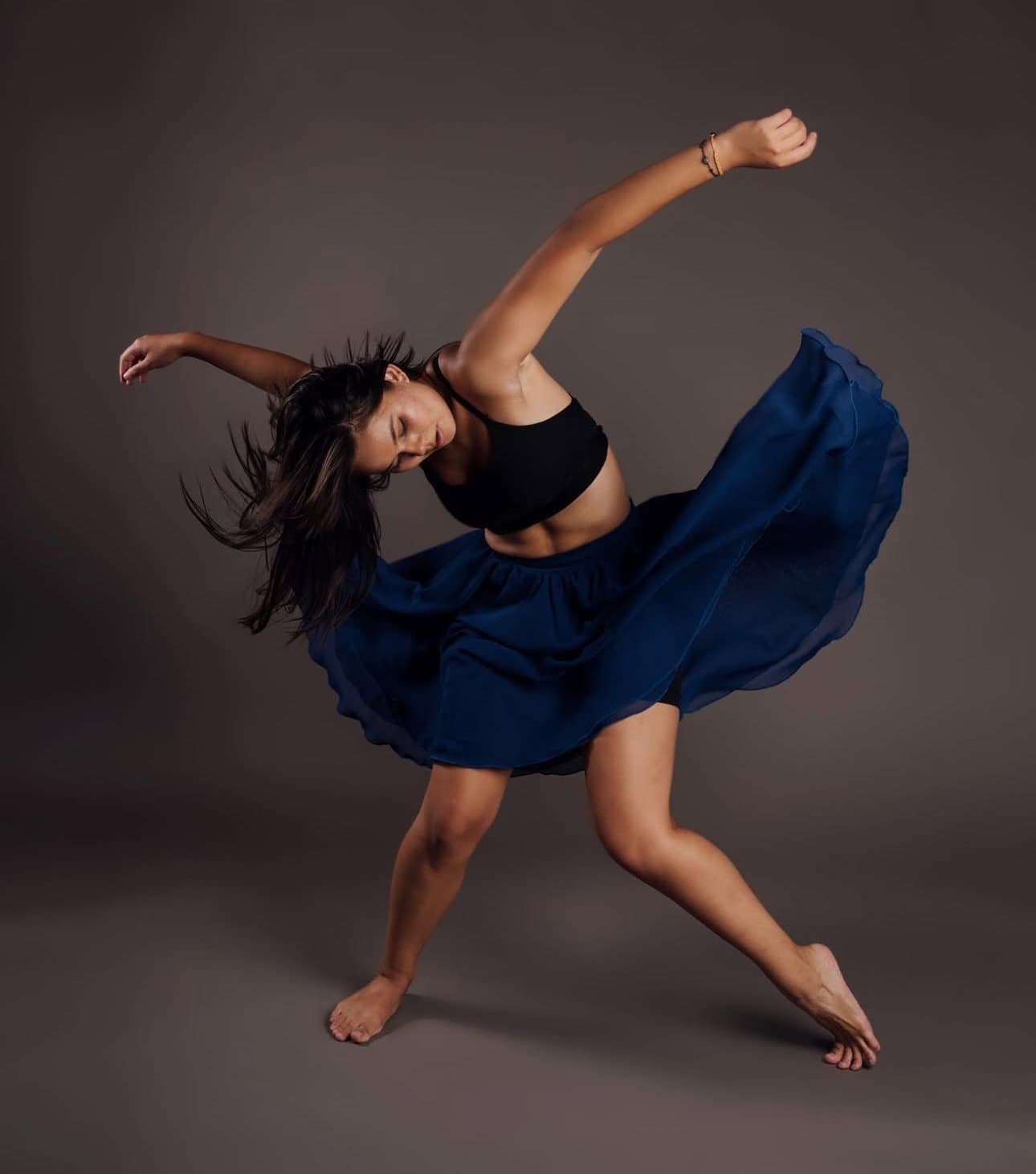 Dancer leaping in a black top and flowing blue skirt